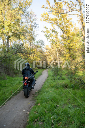 A person riding a motorcycle down a dirt road A person riding a motorcycle down a dirt road 127419927