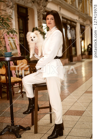 A person standing in front of a building, The girl is holding a spitz dog. A person standing in front of a building, The girl is holding a spitz dog. 127419978