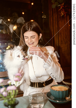 A person sitting at a table with a dog A person sitting at a table with a dog 127419991