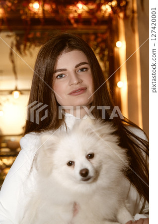 girl standing and holding a cute white dog in her arms girl standing and holding a cute white dog in her arms 127420001