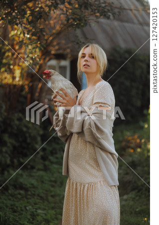 Country woman holding a chicken in her hands.  127420153