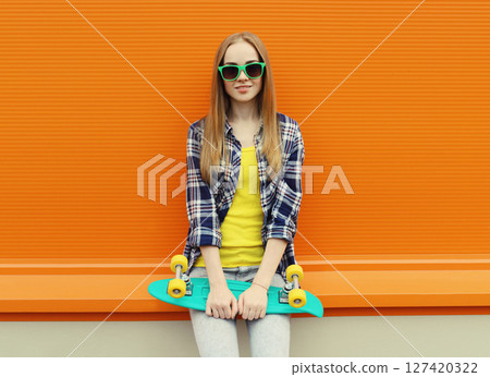 Stylish young woman with skateboard, modern teenage girl posing on city street 127420322