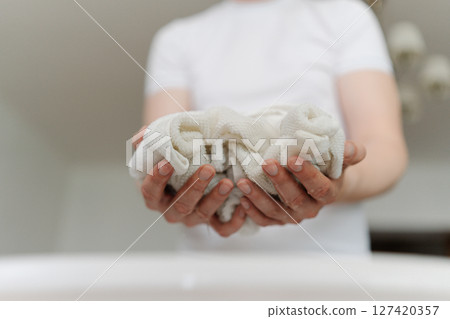 Close-up cropped shot of unrecognizable man soaking dirty white clothes in plastic basin, preparing for laundry with stain remover, closeup. Concept of household chores and daily routines. 127420357