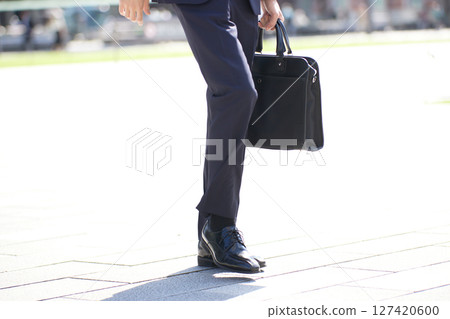 A young businessman in a suit walking through a business district A young businessman in a suit walking through a business district 127420600