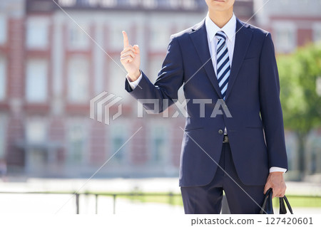 一位西裝革履的年輕商人在商業區指著某樣東西 一位西裝革履的年輕商人在商業區指著某樣東西 127420601