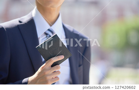 一位身著西裝手拿錢包的年輕商人 一位身著西裝手拿錢包的年輕商人 127420602