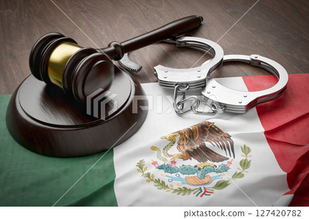 Gavel and Handcuffs Resting on a Tattered and Dirty Mexican Flag. 127420782