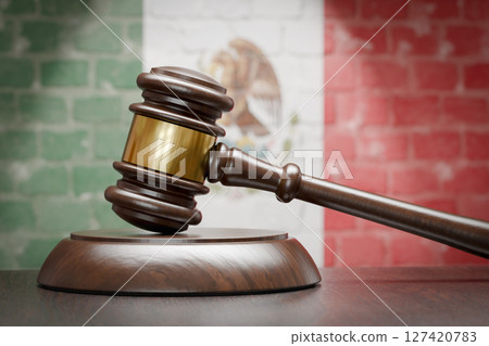 Wooden Gavel Resting on Table In Front of A Brick Wall with Mexican Flag. Wooden Gavel Resting on Table In Front of A Brick Wall with Mexican Flag. 127420783