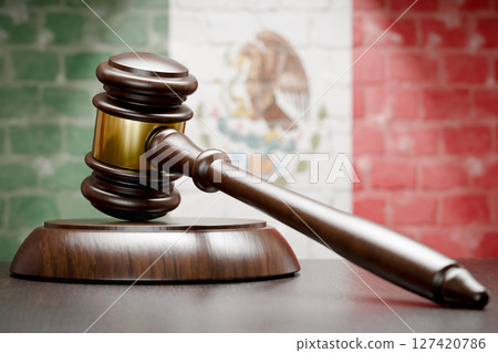 Wooden Gavel Resting on Table In Front of A Brick Wall with Mexican Flag. Wooden Gavel Resting on Table In Front of A Brick Wall with Mexican Flag. 127420786