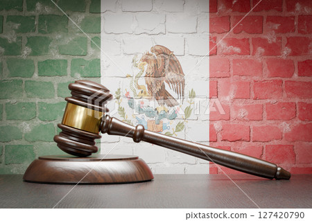 Wooden Gavel Resting on Table In Front of A Brick Wall with Mexican Flag. 127420790