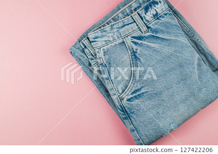 Folded denim jeans on a pastel surface Folded denim jeans on a pastel surface 127422206
