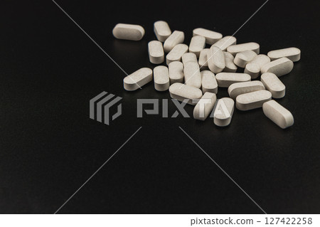 Tablets scattered on a dark surface depicting health supplements 127422258