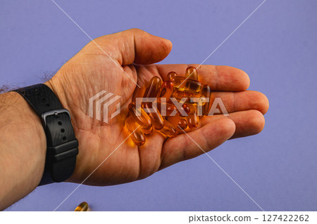 Hand holding gel capsules on purple background Hand holding gel capsules on purple background 127422262