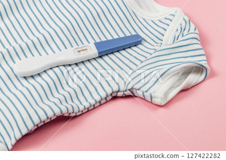 Pregnancy test on striped onesie with pink backdrop 127422282