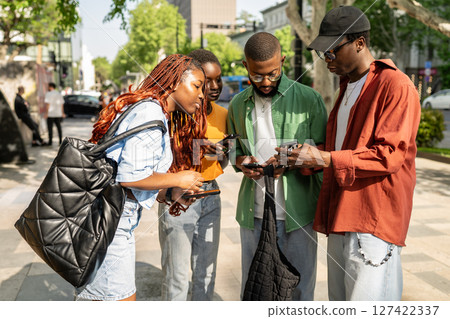Interested group of african american friends students search info online using phones while walking. 127422337