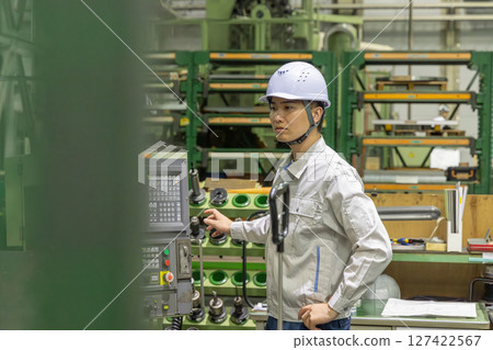 A worker operating a machine on a factory control panel 127422567