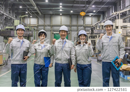 Workers pumping their fists in a factory Workers pumping their fists in a factory 127422581