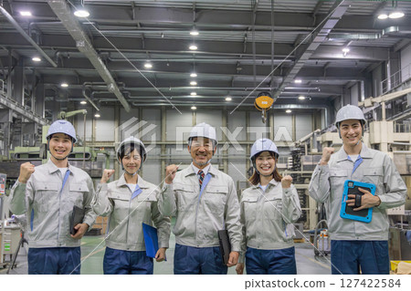 Workers pumping their fists in a factory Workers pumping their fists in a factory 127422584