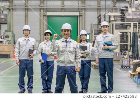 Workers pumping their fists in a factory Workers pumping their fists in a factory 127422588