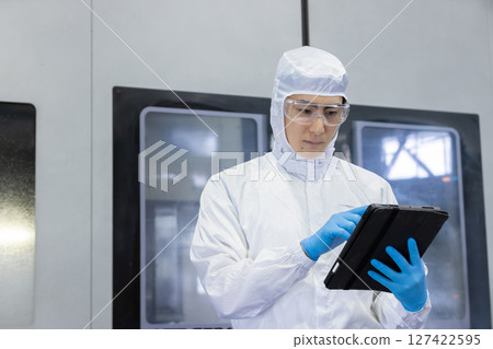 Worker in protective clothing using tablet PC in factory 127422595