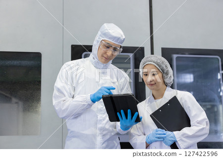 Worker in protective clothing using tablet PC in factory 127422596