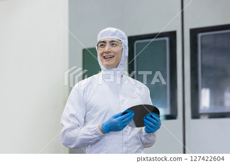工廠裡穿著防護衣的工人拿著矽片 工廠裡穿著防護衣的工人拿著矽片 127422604
