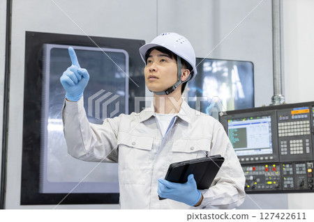Male worker working in front of a factory control panel 127422611