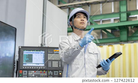 Male worker working in front of a factory control panel 127422612