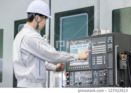 Male worker working in front of a factory control panel 127422613
