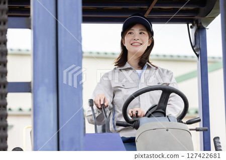 Female worker driving a forklift Female worker driving a forklift 127422681