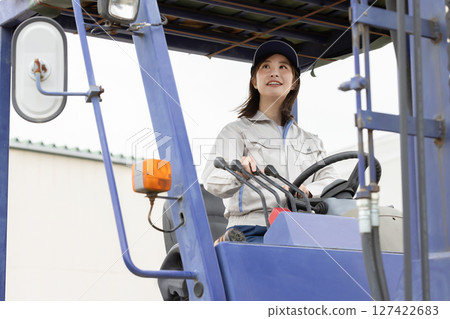 Young woman driving a forklift in a warehouse Young woman driving a forklift in a warehouse 127422683