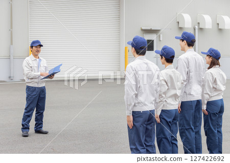 A group of workers having a morning meeting in front of the factory A group of workers having a morning meeting in front of the factory 127422692