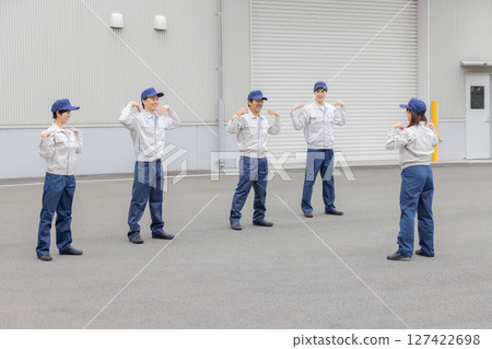 A group of workers doing exercises in front of a factory A group of workers doing exercises in front of a factory 127422698
