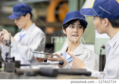 A group of workers operating machine tools in a factory A group of workers operating machine tools in a factory 127422714