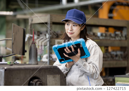 A worker inspecting a machine using a tablet PC A worker inspecting a machine using a tablet PC 127422715