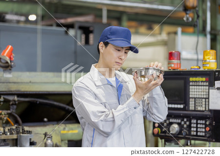 A male worker checking lathe-finished and milled products at a factory A male worker checking lathe-finished and milled products at a factory 127422728