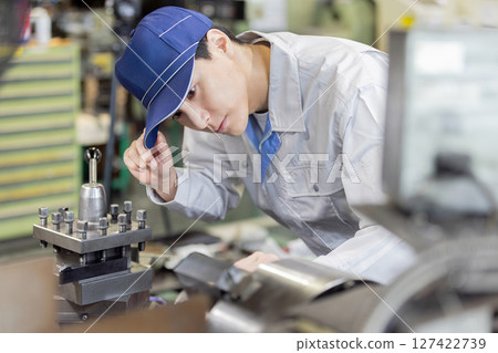 Male worker operating a machine in a factory 127422739