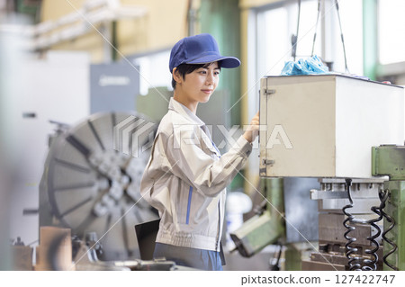 一名女工在控制面板上操作工廠機器 127422747