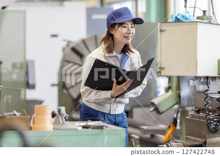 一名女工在控制面板上操作工廠機器 一名女工在控制面板上操作工廠機器 127422748