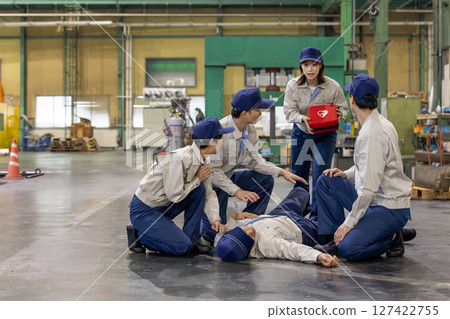 A group of people using an AED to help a worker who collapsed at a factory A group of people using an AED to help a worker who collapsed at a factory 127422755