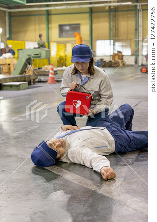 一名女工使用 AED 幫助一名在工廠暈倒的工人 一名女工使用 AED 幫助一名在工廠暈倒的工人 127422756