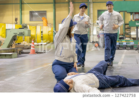 A female worker finds a worker who has collapsed at a factory and calls for help 127422758
