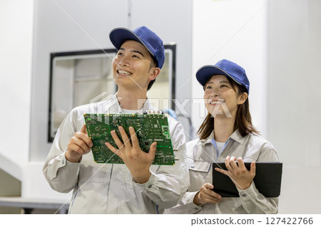 Male and female workers inspecting products using a tablet in a factory 127422766