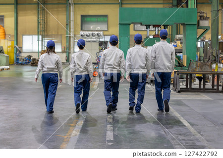 Rear view of a group of workers walking side by side in a factory 127422792
