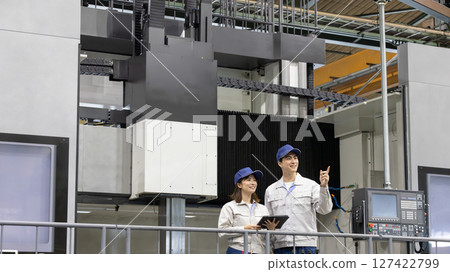 Male and female workers working in front of one of Japan's largest lathe machines Male and female workers working in front of one of Japan's largest lathe machines 127422799