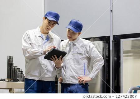 一群工人正在使用平板電腦檢查機器 127422807