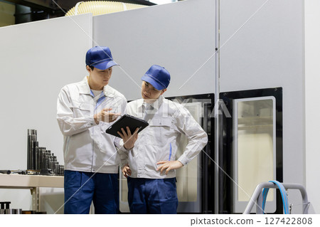 一群工人正在使用平板電腦檢查機器 127422808