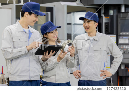 工廠裡一群工人正在檢查車床加工和銑削的產品 127422810