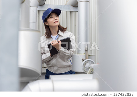 A female worker inspecting outdoor machinery A female worker inspecting outdoor machinery 127422822