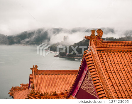 廟宇橘色屋頂與起霧的湖邊背景 127423095